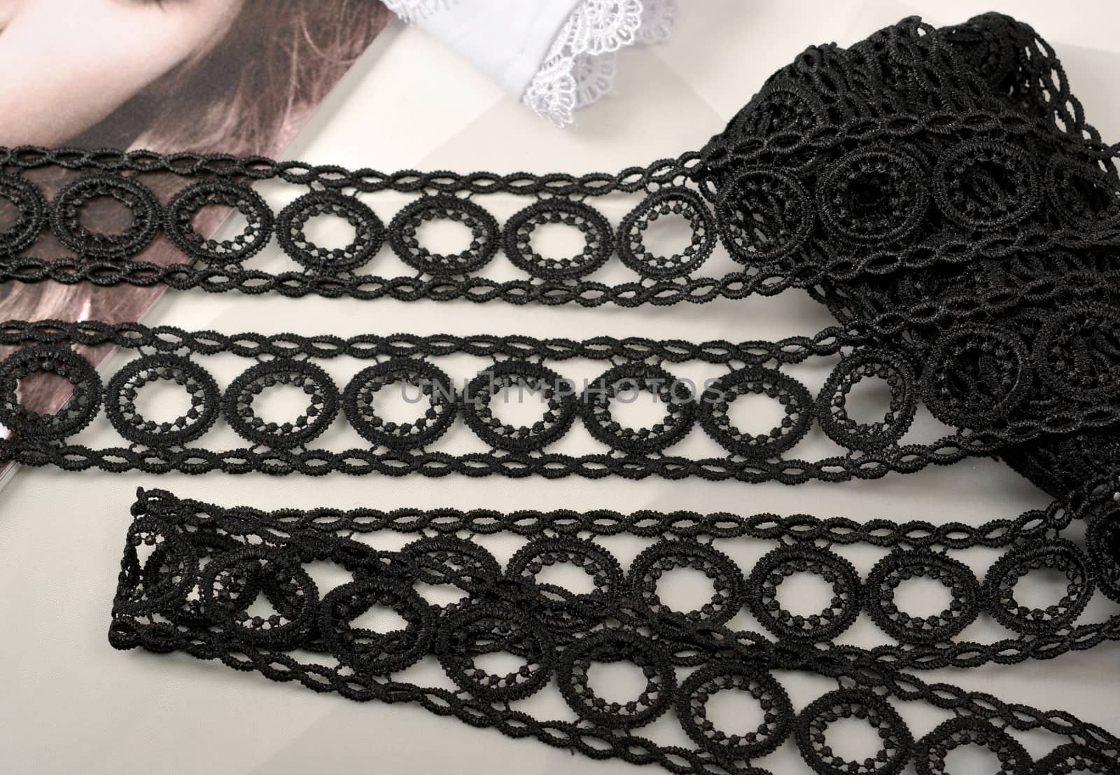 Tapes of black gentle guipure, beauty lace fabric on light background. Elastic material. Using for Atelier and needlework store.