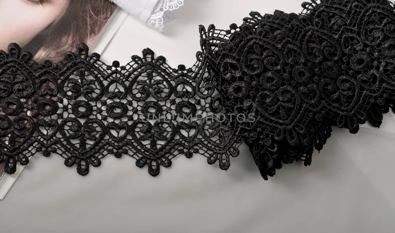 Tapes of black gentle guipure, beauty lace fabric on light background. Elastic material. Using for Atelier and needlework store.