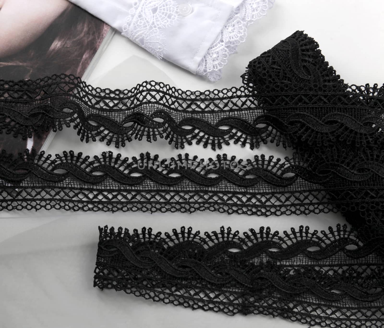 Tapes of black gentle guipure, beauty lace fabric on light background. Elastic material. Using for Atelier and needlework store.