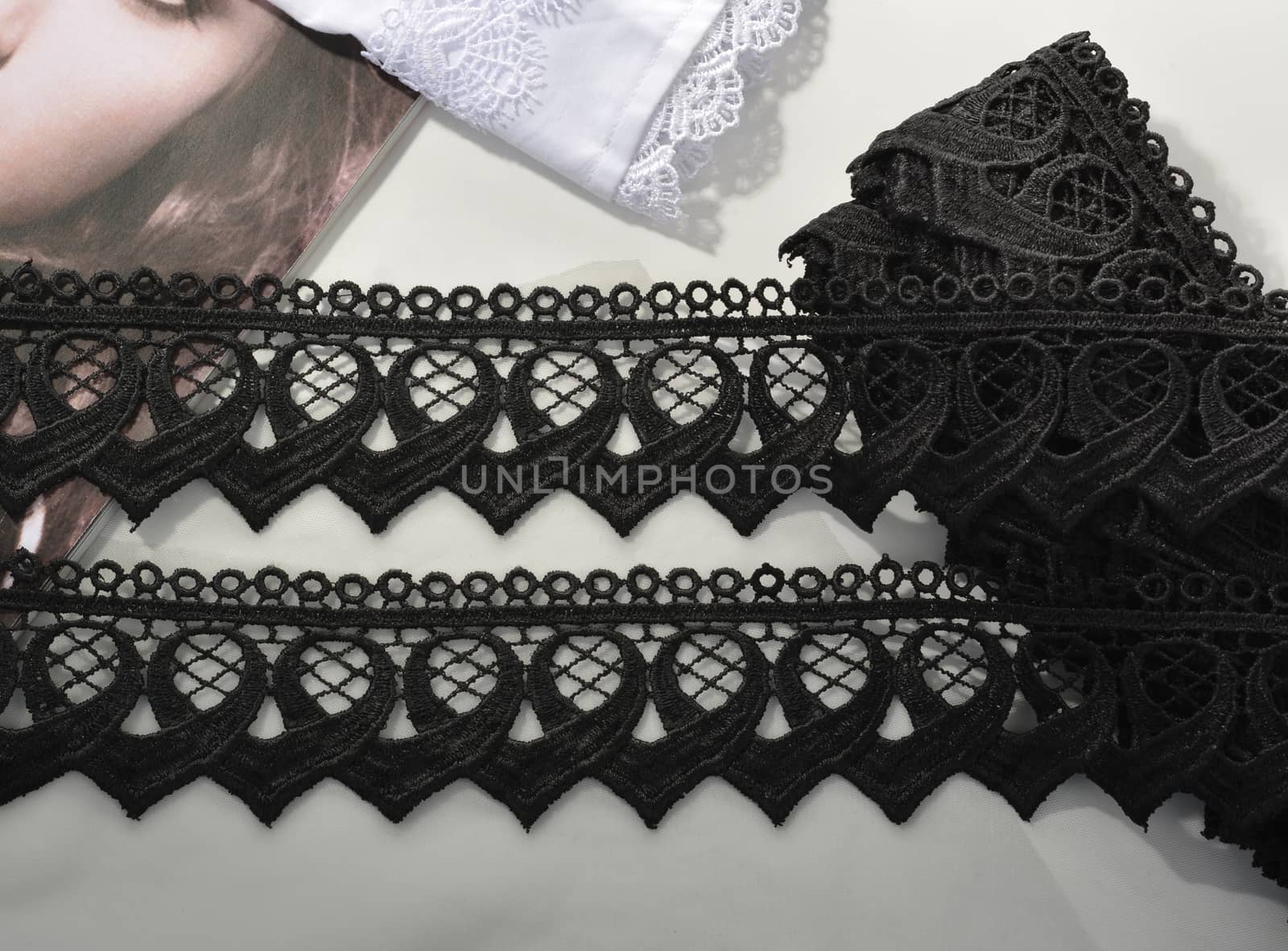 Tapes of black gentle guipure, beauty lace fabric on light background. Elastic material. Using for Atelier and needlework store.