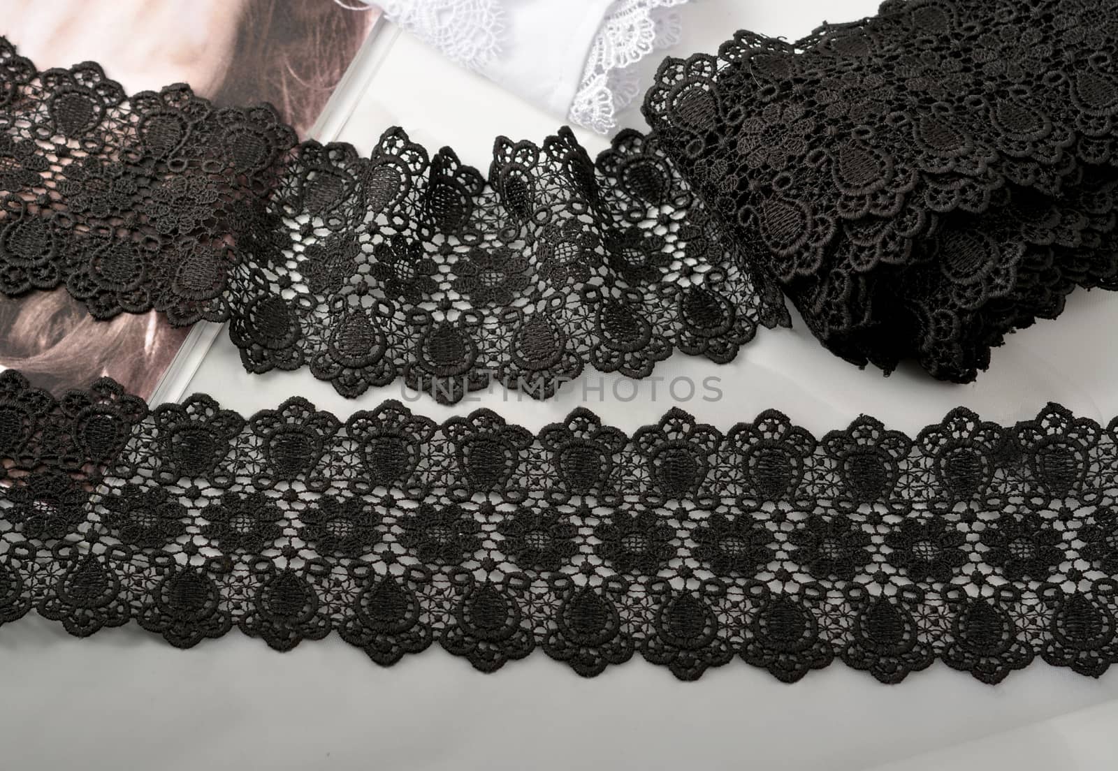 Tapes of black gentle guipure, beauty lace fabric on light background. Elastic material. Using for Atelier and needlework store.