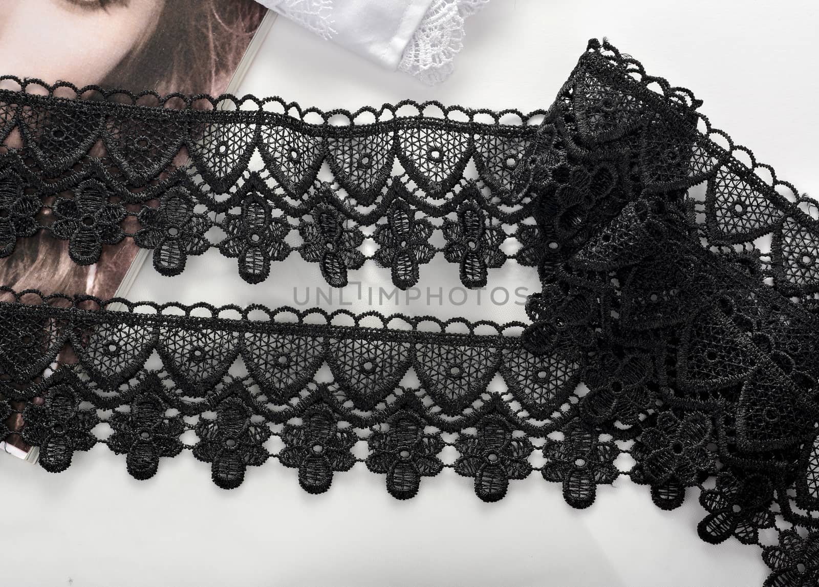 Tapes of black gentle guipure, beauty lace fabric on light background. Elastic material. Using for Atelier and needlework store.