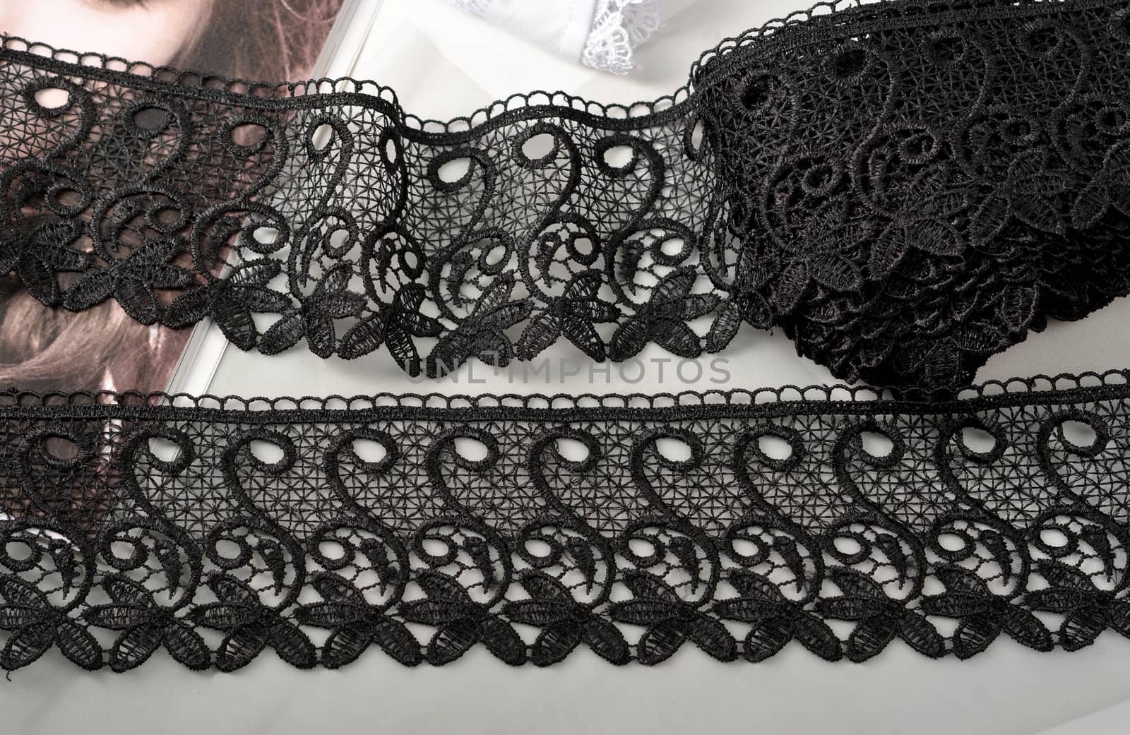 Tapes of black gentle guipure, beauty lace fabric on light background. Elastic material. Using for Atelier and needlework store.