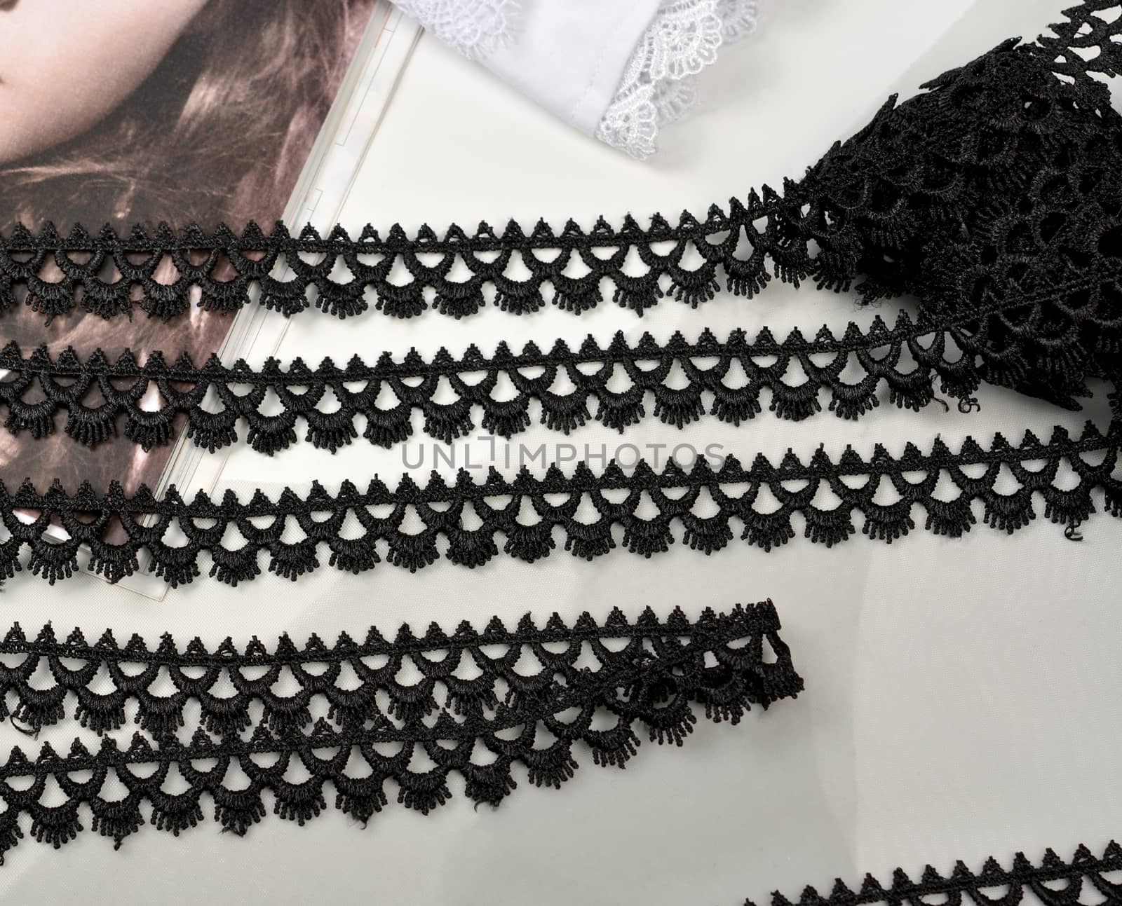 Tapes of black gentle guipure, beauty lace fabric on light background. Elastic material. Using for Atelier and needlework store.