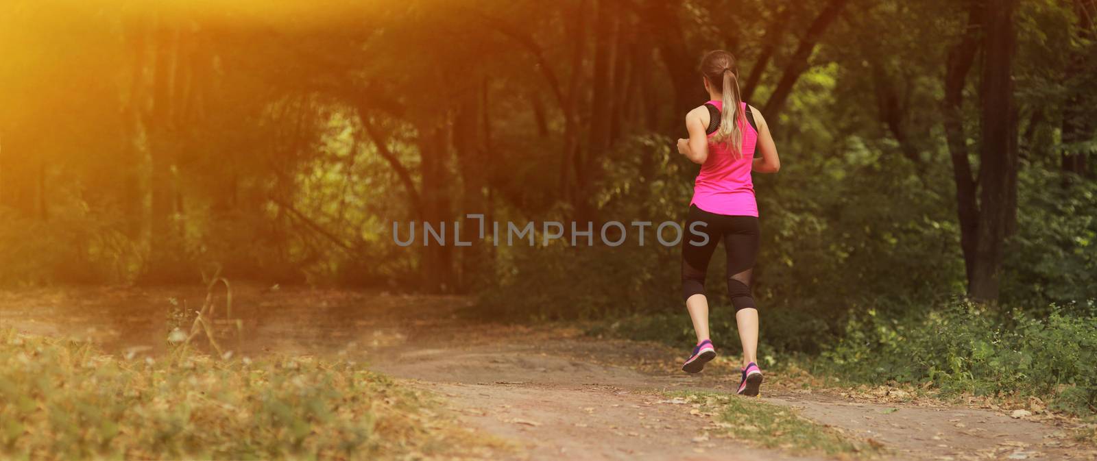 Young fitness woman running in the morning forest trail. Healthy fit living. by selinsmo