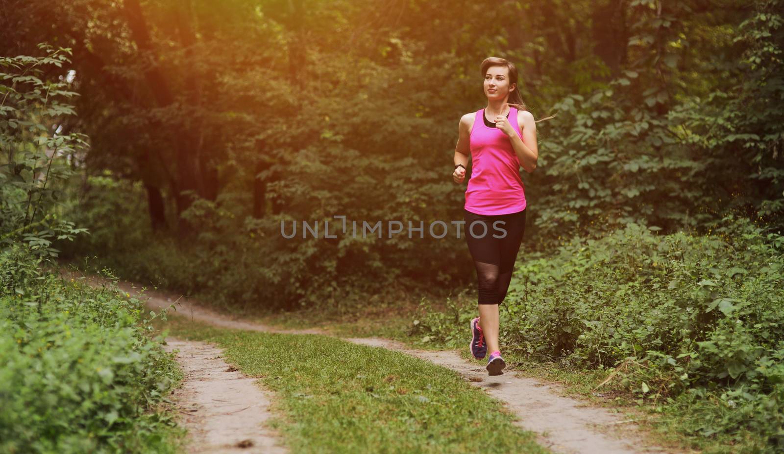 Young fitness woman running in the morning forest trail. Motivation healthy fit living. Running shoe of the person running in nature with beautiful sunlight. Woman warming up before running