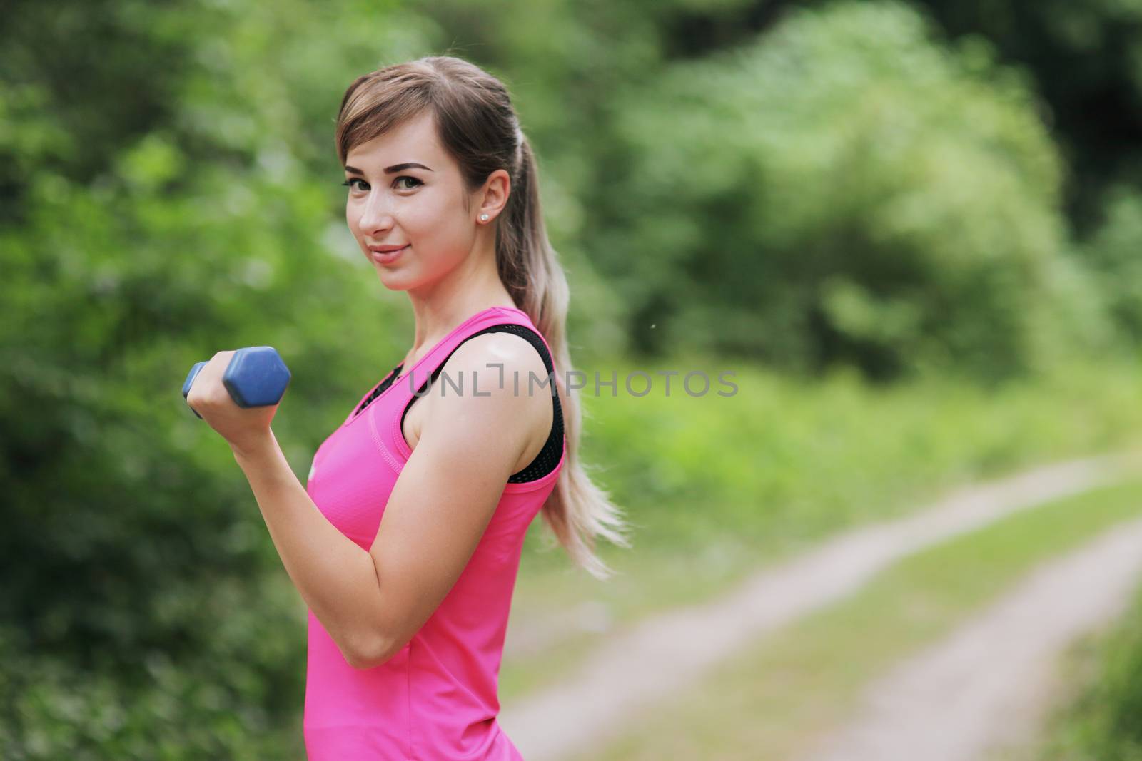The girl is engaged in sports with weights in nature forest. Motivation healthy fit living. Running shoe of the person running in nature with beautiful sunlight. Woman warming up before running