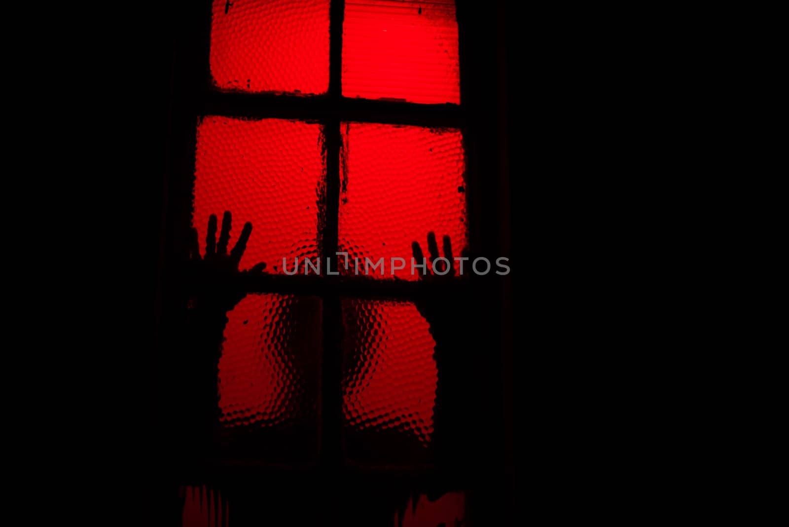 Scary sihouette of person leaning against window in dark