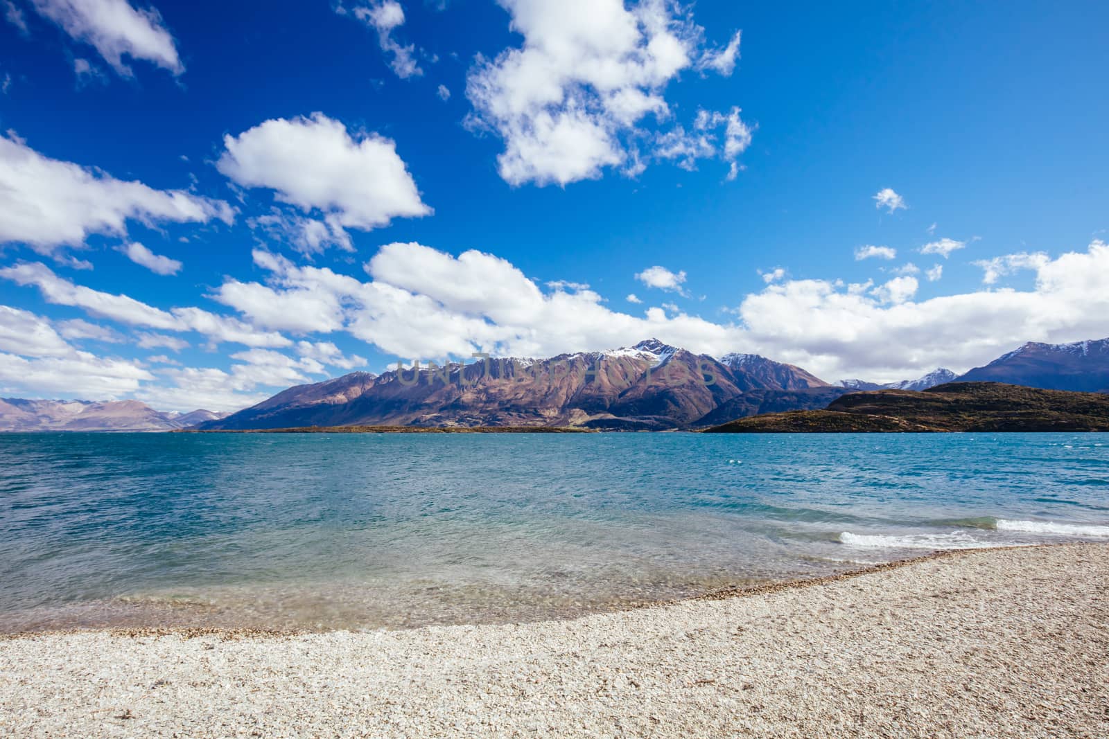 Lake Wakatipu and surrounding mountains from Twenty Five Mile Stream campground, on a sunny spring day near Glenorchy in New Zealand