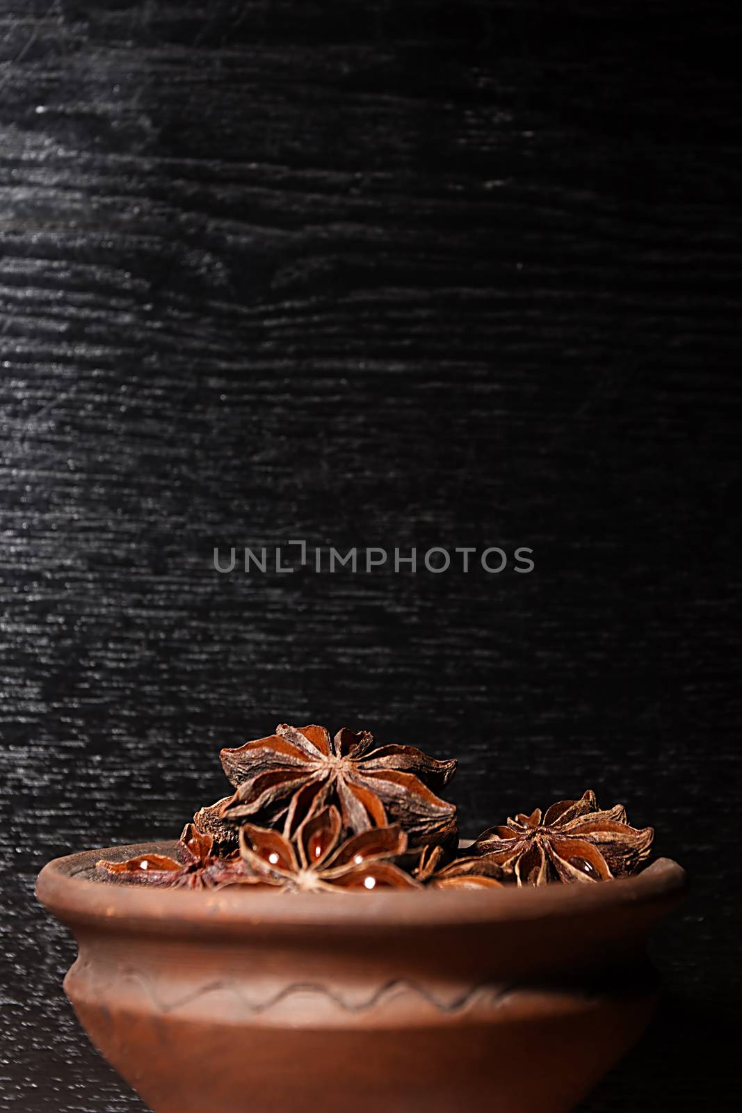 Anis in bowl, dark background, selective focus
