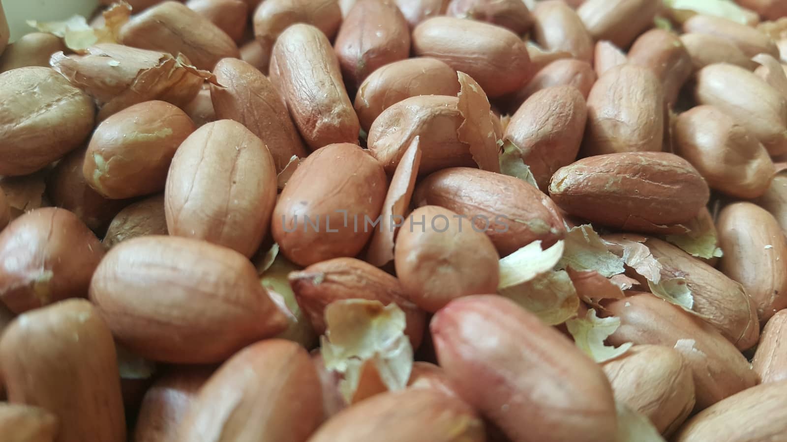Closeup view of mixed, dried, roasted  peeled and unpeeled peanuts. A fruit for background text