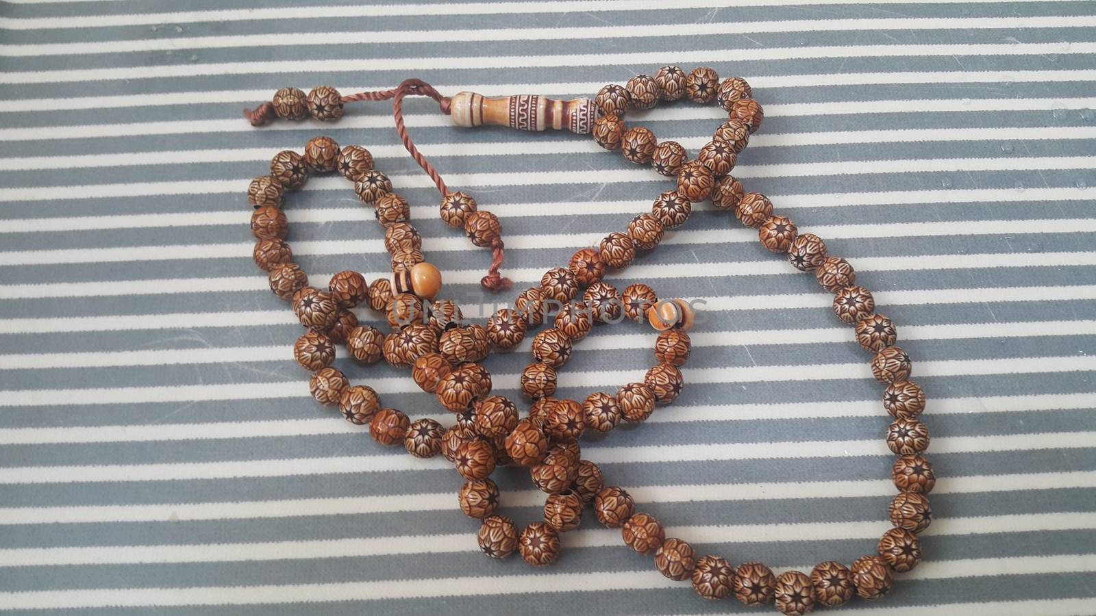 Beautiful wooden prayer beads or rosary with a striped background. Religion concept of ramadan or Eid for muslims.