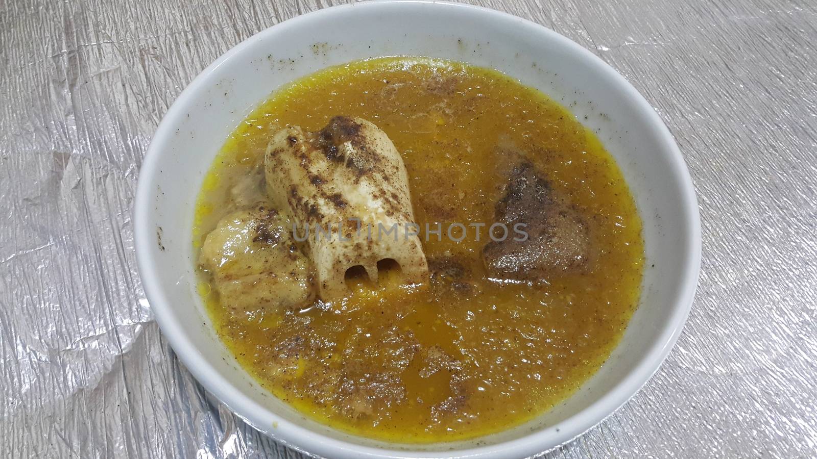 Top view of siri paaye or paya dish garnished with diced ginger, long coriander leaves and fresh sliced lemon. This dish is popular in Pakistan and Bangladesh