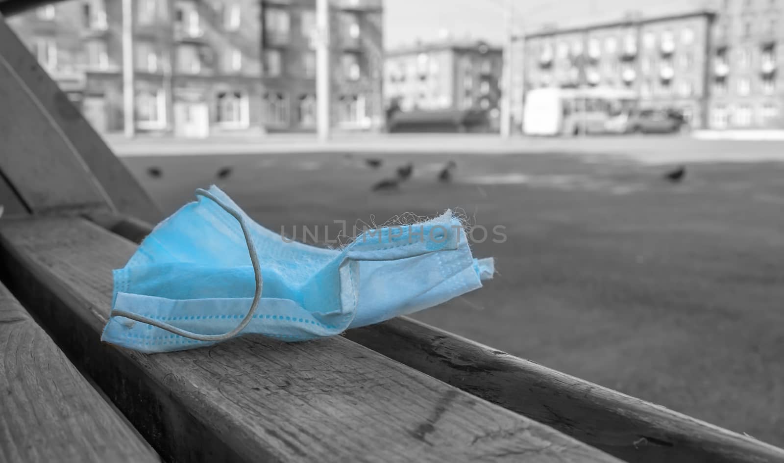 an abandoned and used antibacterial medical mask lies on a bench in a city Park