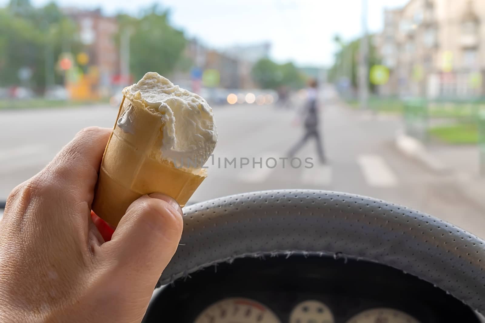 a driver holds an ice cream while driving while approaching a pedestrian crossing