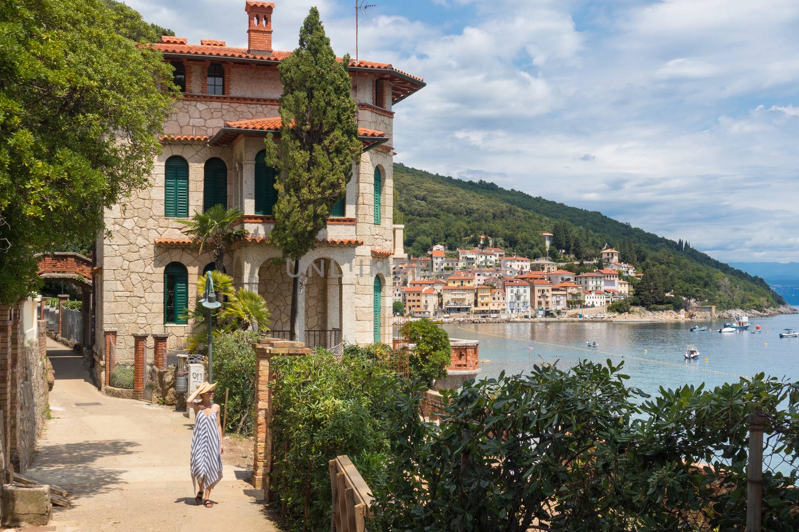 Female tourist walking along Adriatic sea coast relaxing on vacation in Moscenicka Draga, Istria, Croatia. by kasto