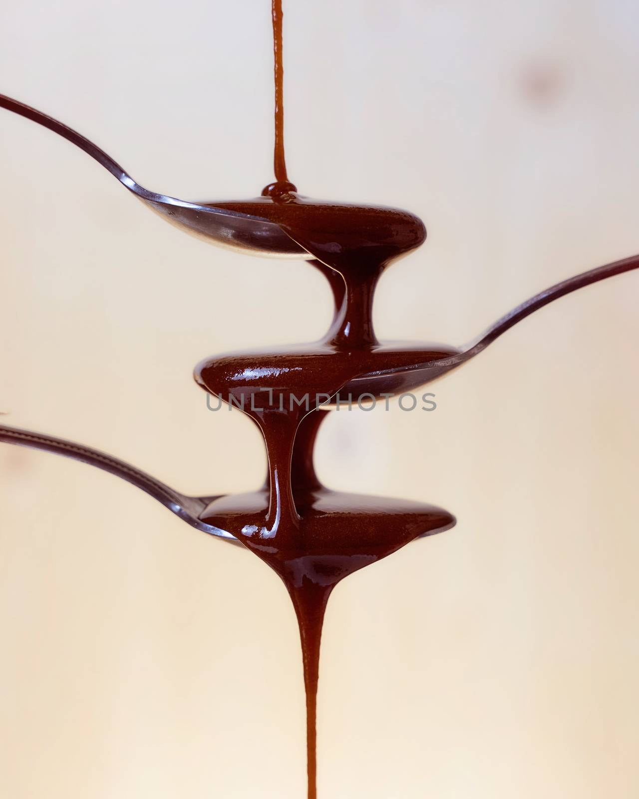 Chocolate cream drains on three spoons on a light background. Close-up. Very high quality photo