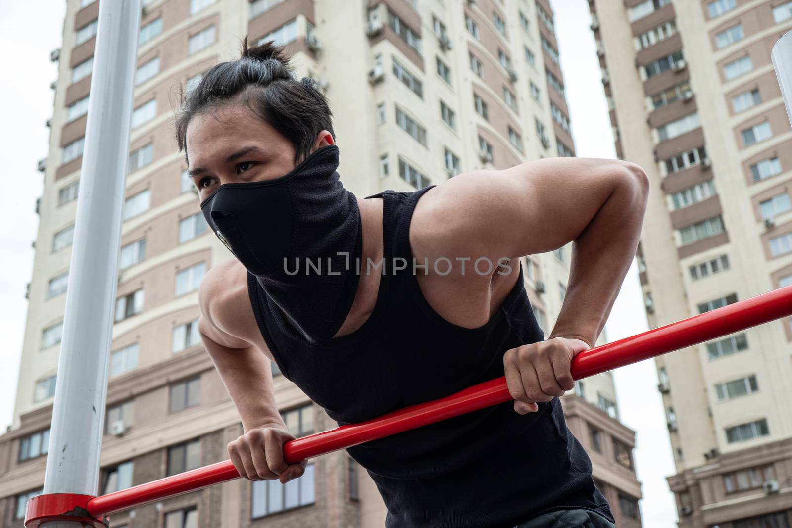 The guy is pushing up on the bars, in a black T-shirt and mask, in quarantine