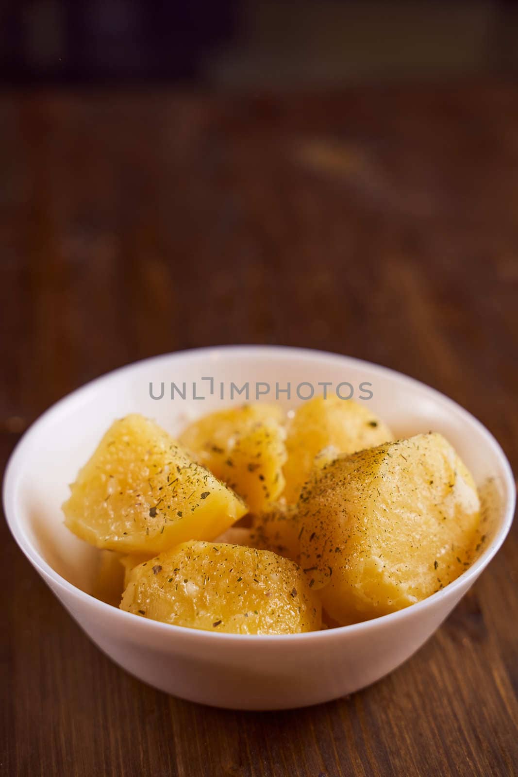 Boiled potatoes with mslom seasonings in a plate on a brown background. High quality photo