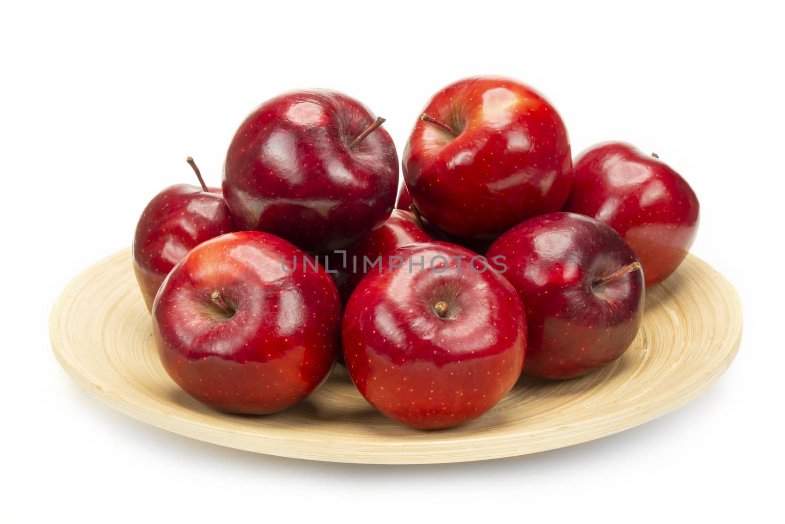 A bunch of fresh red apples on a bamboo plate, isolated on white background.