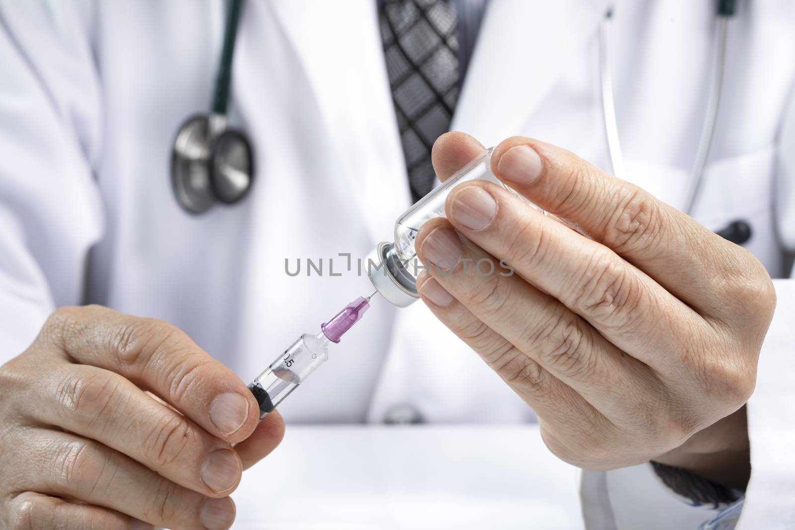 A male doctor using a syringe to draw fluid or vaccine from a vial. Medication or vaccination administration concept. Covid vaccine concept. Asian ethnicity.