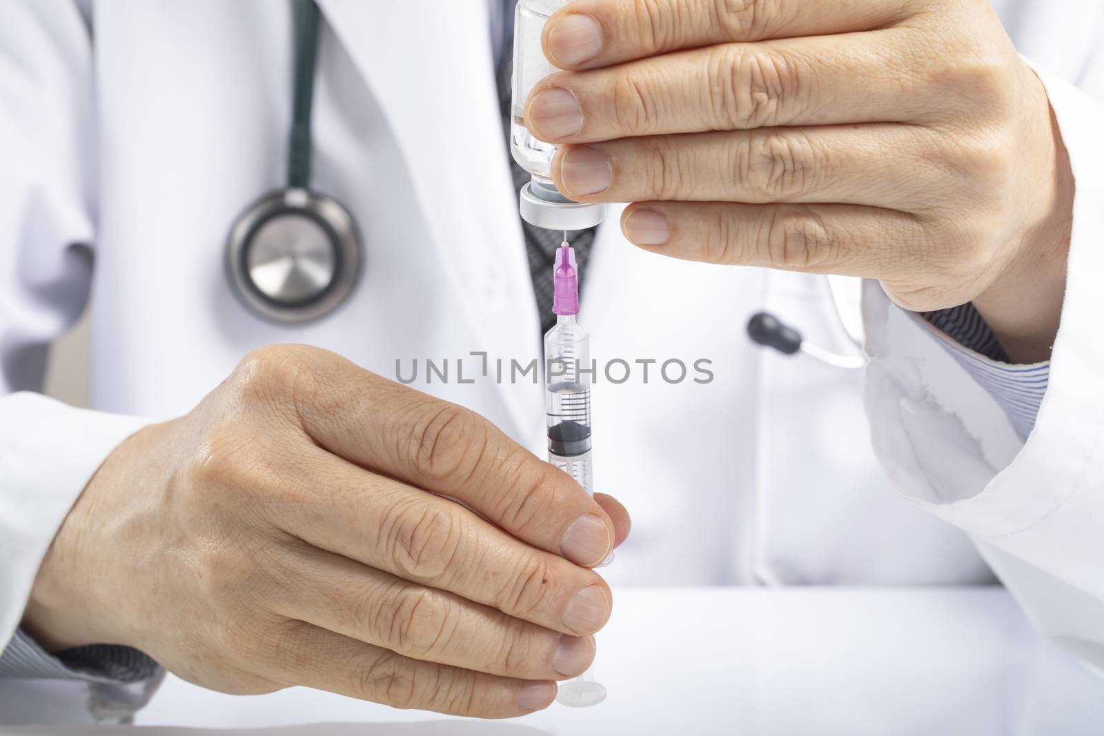 A male doctor using a syringe to draw fluid or vaccine from a vial. Medication or vaccination administration concept. Covid vaccine concept. Asian ethnicity.