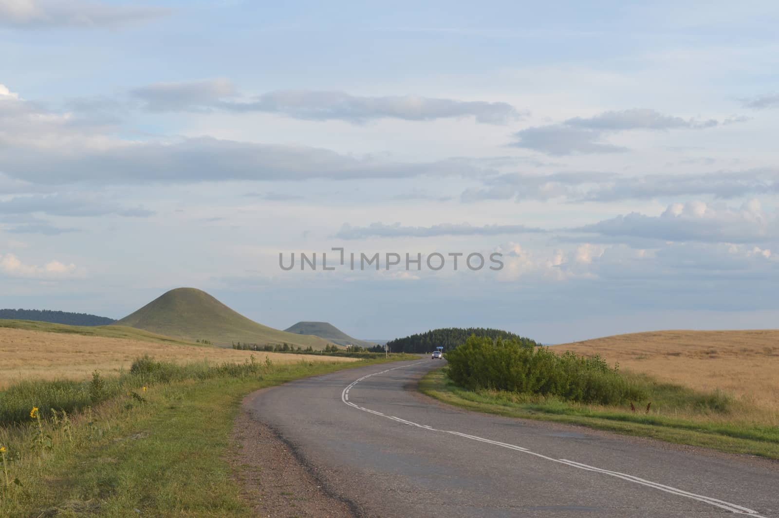summer landscape with road, mountain and blue sky with clouds