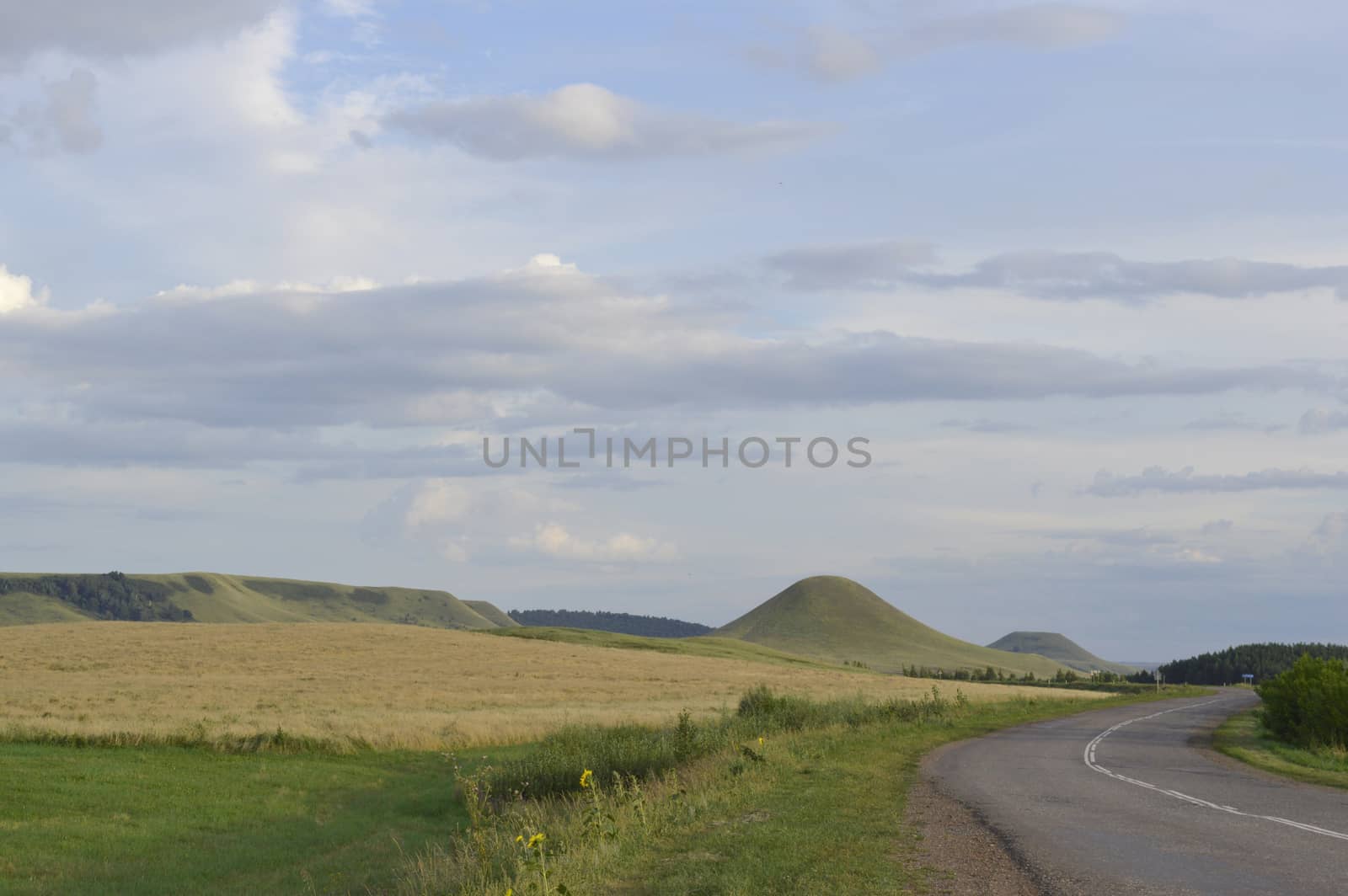 summer landscape with road, mountain and blue sky with clouds