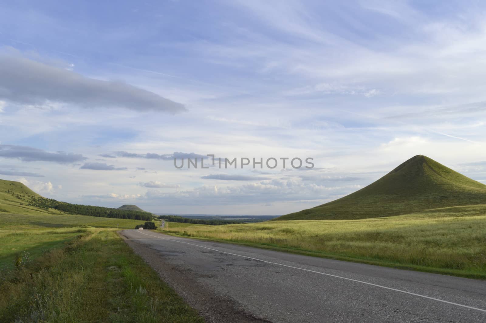 summer landscape with road, mountain and blue sky with clouds