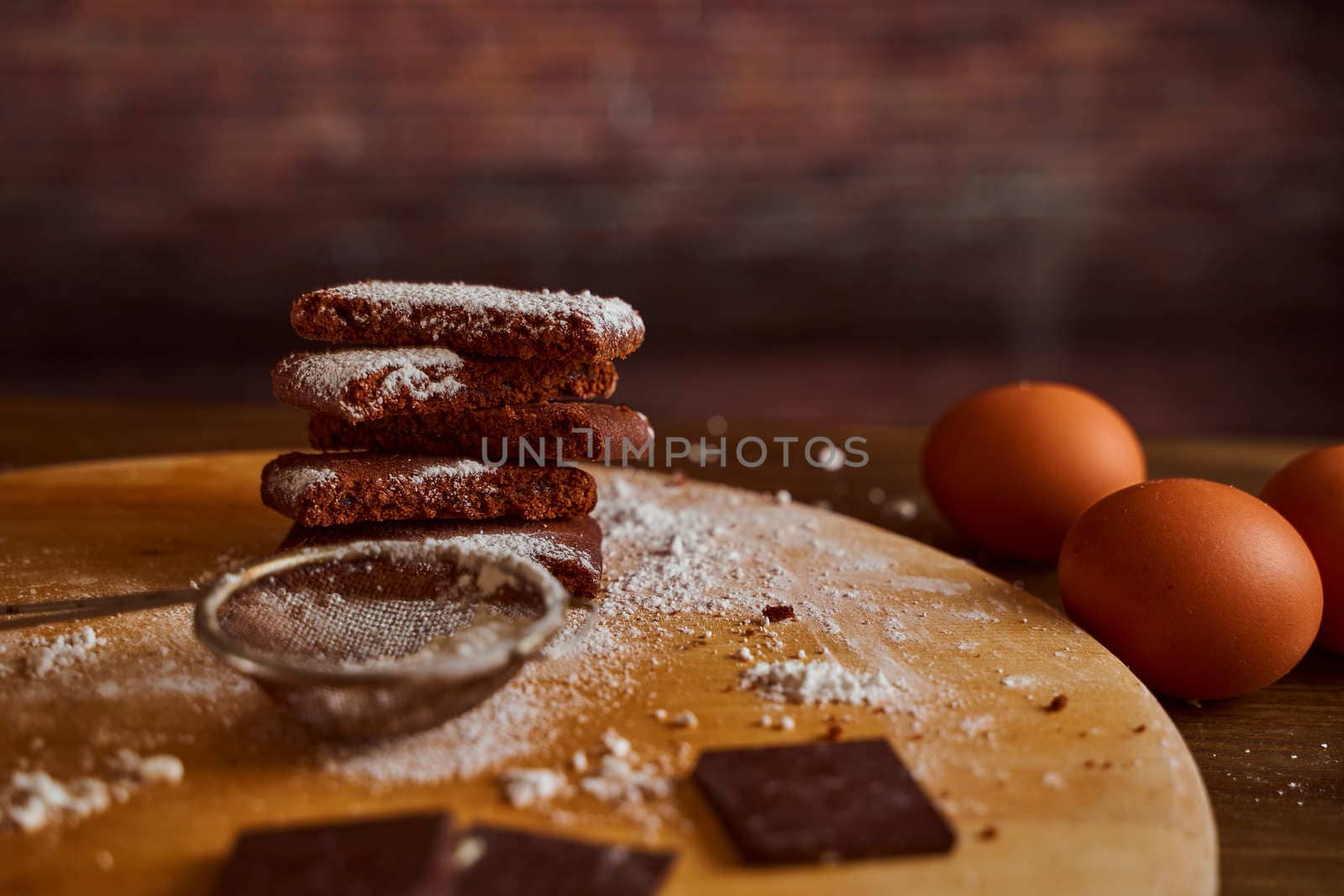 Chocolate cakes stacked on a wooden table. next to it are eggs and pieces of chocolate. blurred background. High quality photo