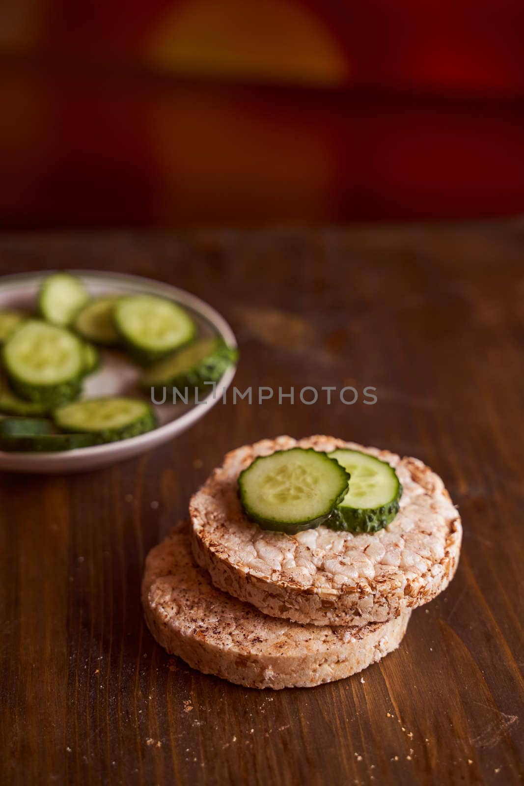 round buckwheat bread on which are two fresh cucumbers on a brown background. High quality photo
