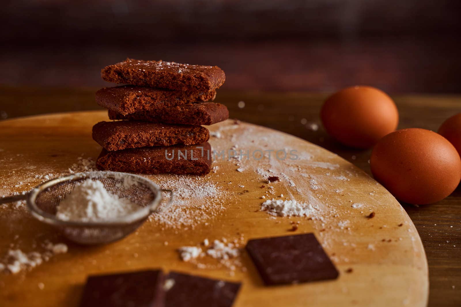 Chocolate cakes stacked on a wooden table. next to it are eggs and pieces of chocolate. blurred background. High quality photo