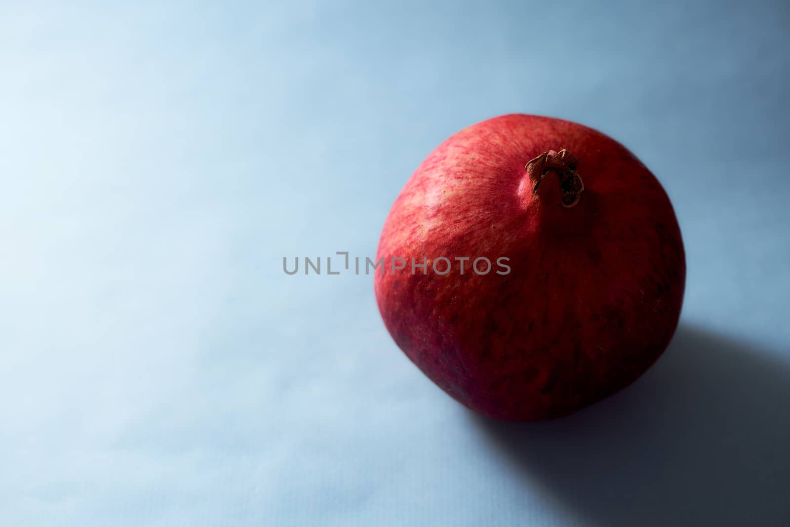 Red ripe pomegranate pours on blue background. High quality photo