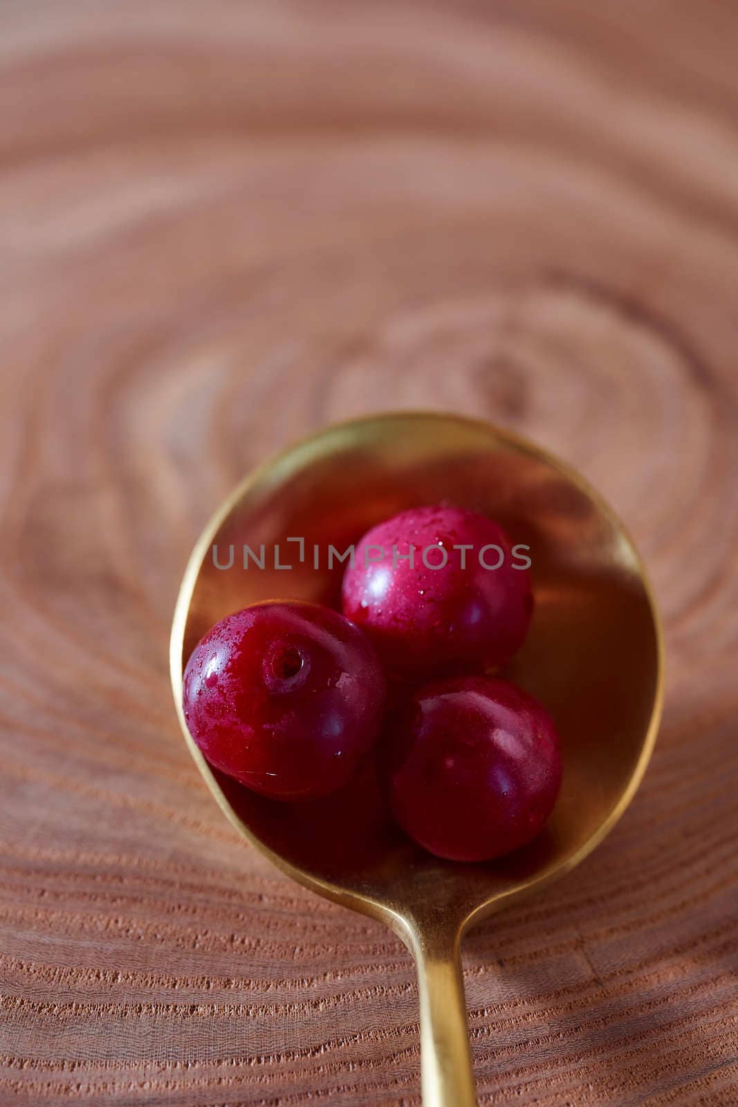 Ripe cherry berry on a wooden slice of wood in golden spoon. High quality photo