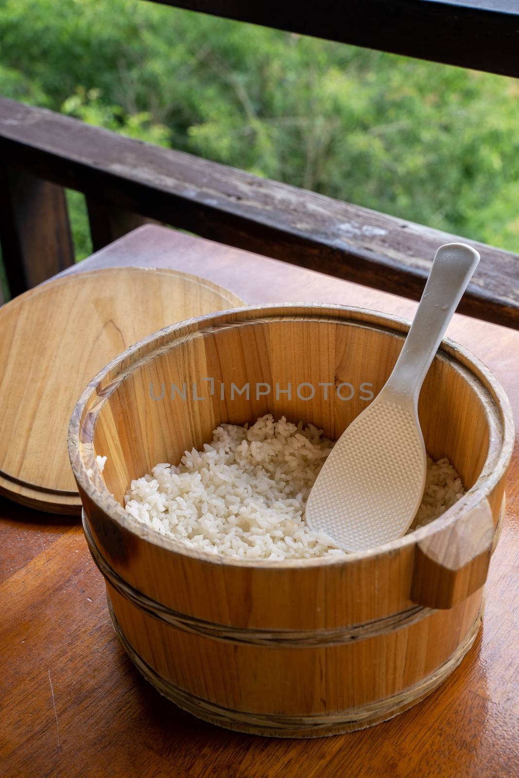 Delicious cooked plain rice in a big wooden bowl ready-to-eat with white rice spatula spoon at restaurant table, close up, lifestyle.