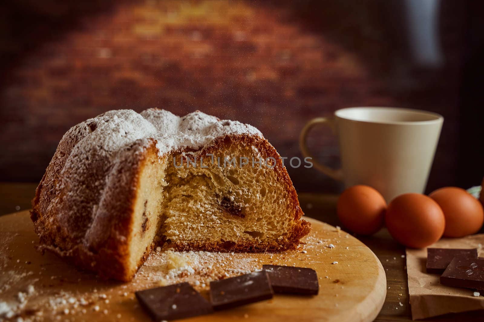 Cut homemade cupcake with chocolate cream inside with eggs and cup of tea on a wooden board. Black background. High quality photo