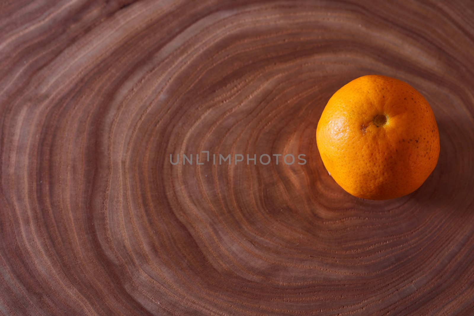 A orange mandarin lies on a slice of a tree. Wooden background. High quality photo