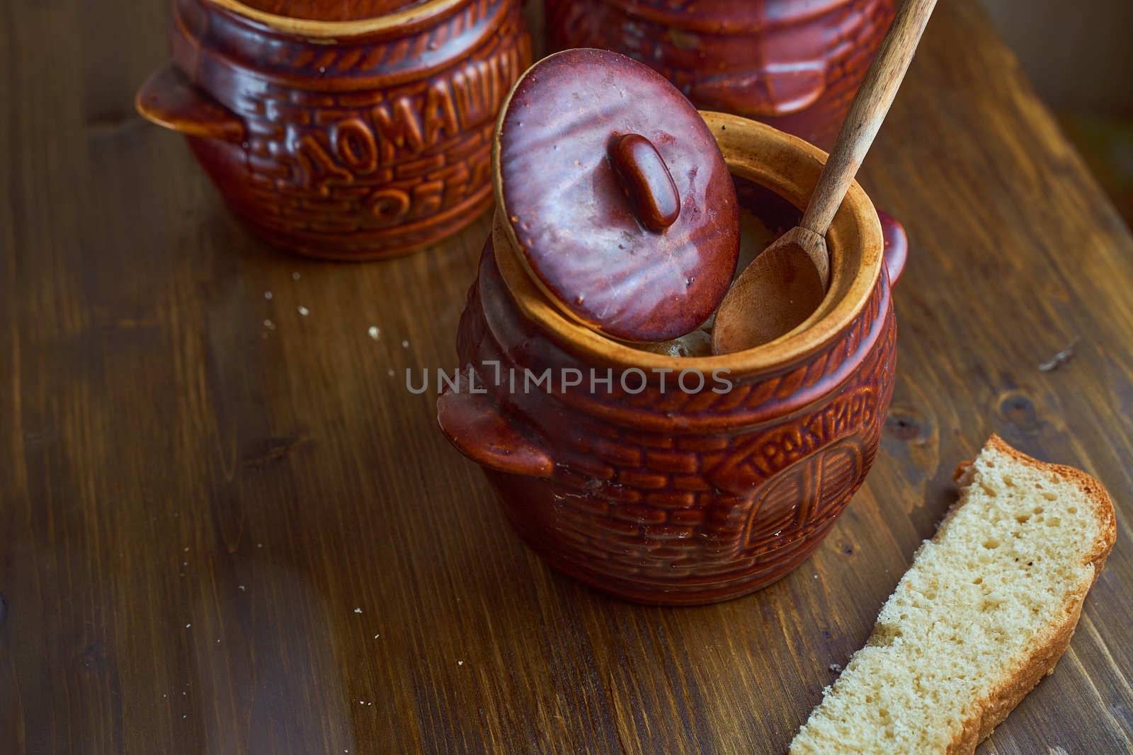 Homemade food. Potatoes and fish in clay pots on a wooden table . High quality photo
