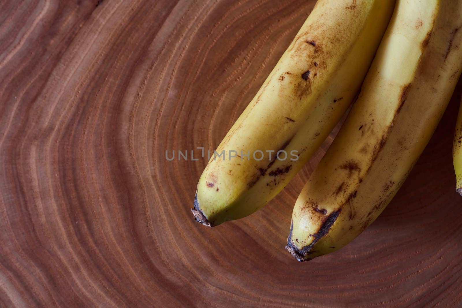 A yellow banana lies on a slice of a tree. Wooden background. High quality photo