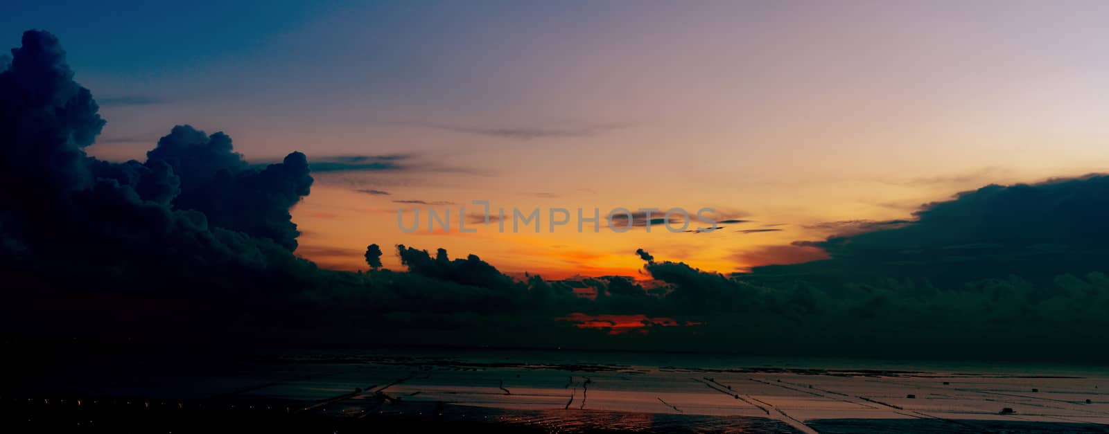 Beautiful cloudscape. Orange, blue, purple and dark dramatic sunset sky over the sea at tide. Landscape of tropical sea in the evening. Summer sunset sky. Beauty in nature with panorama view.