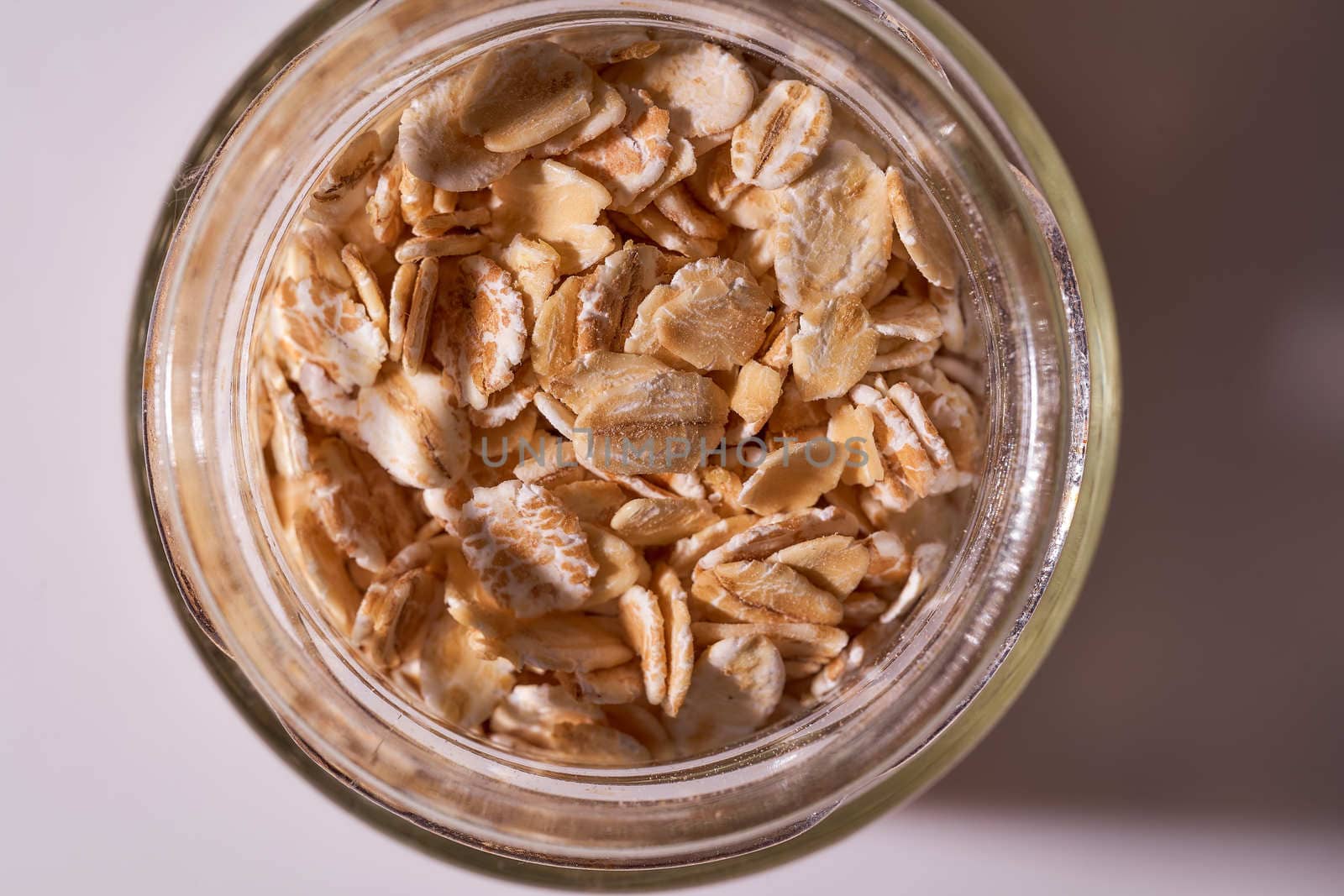 Oat flakes lie in a snitch jar on a white background. High quality photo
