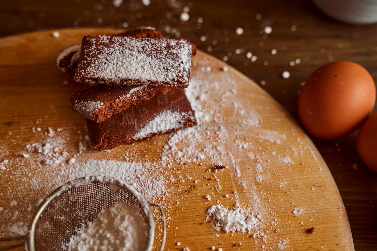 Chocolate cakes stacked on a wooden table. next to it are eggs and pieces of chocolate. blurred background. High quality photo