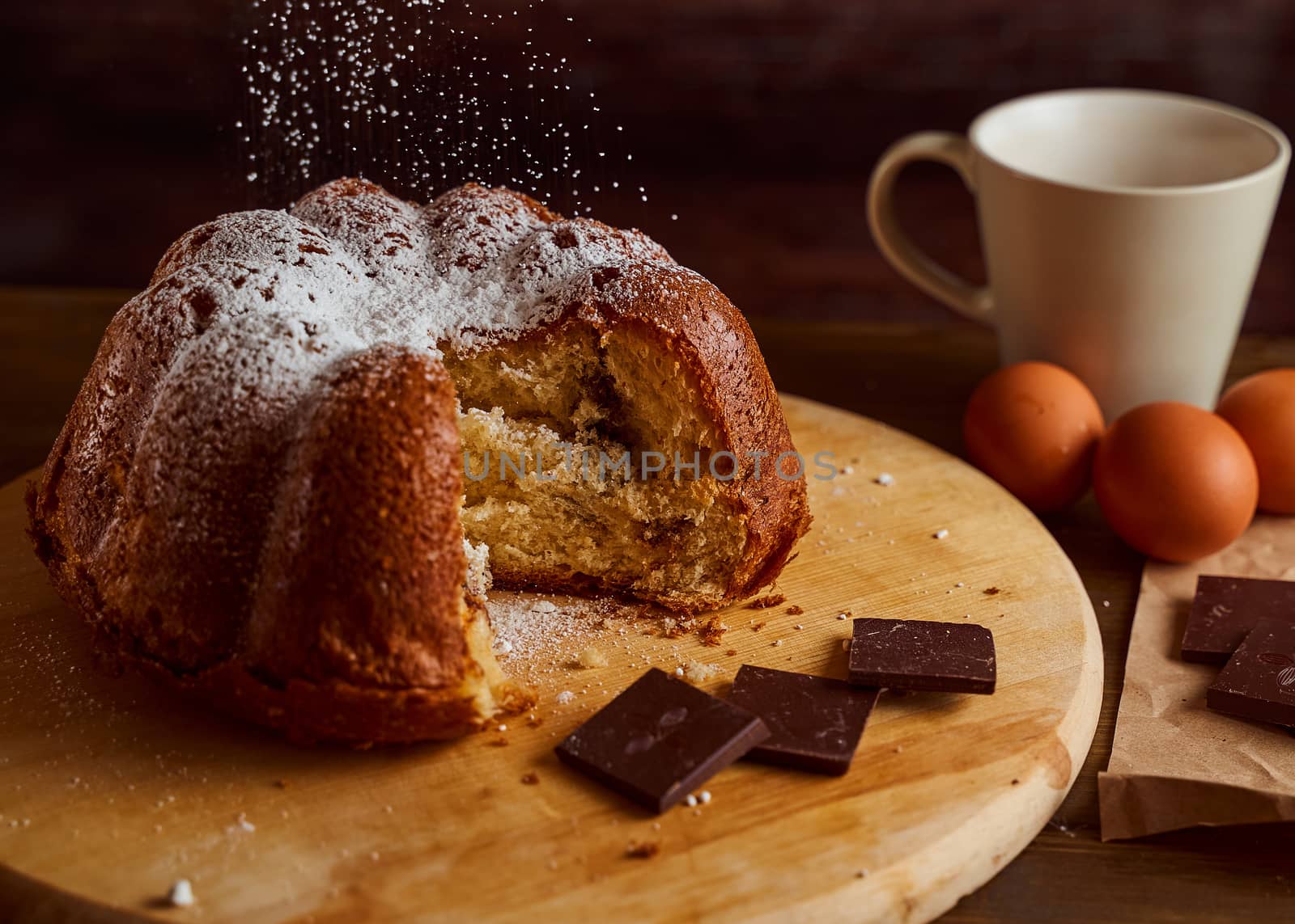 Cut homemade cupcake with chocolate cream inside sprinkled with powdered sugar on a wooden board. Close-up.. High quality photo