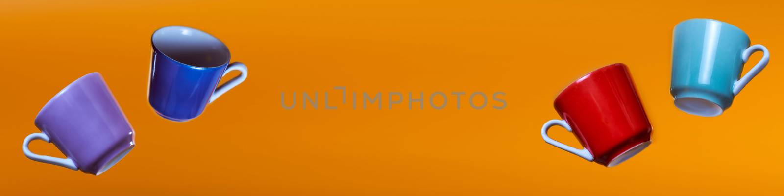 Advertising banner multicolored coffee cups on an orange background. High quality photo