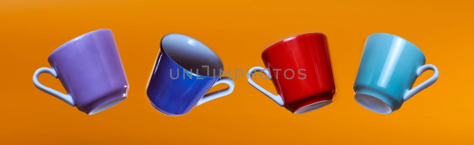 Advertising banner multicolored coffee cups on an orange background. High quality photo