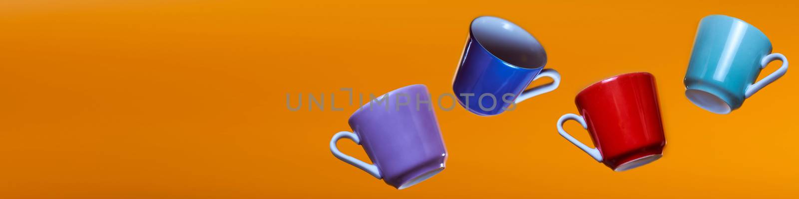 Advertising banner multicolored coffee cups on an orange background. High quality photo