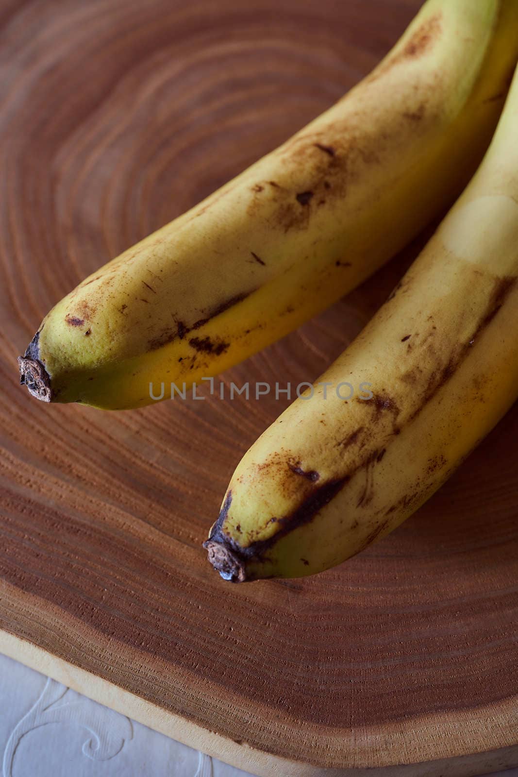 A yellow banana lies on a slice of a tree. Wooden background. High quality photo