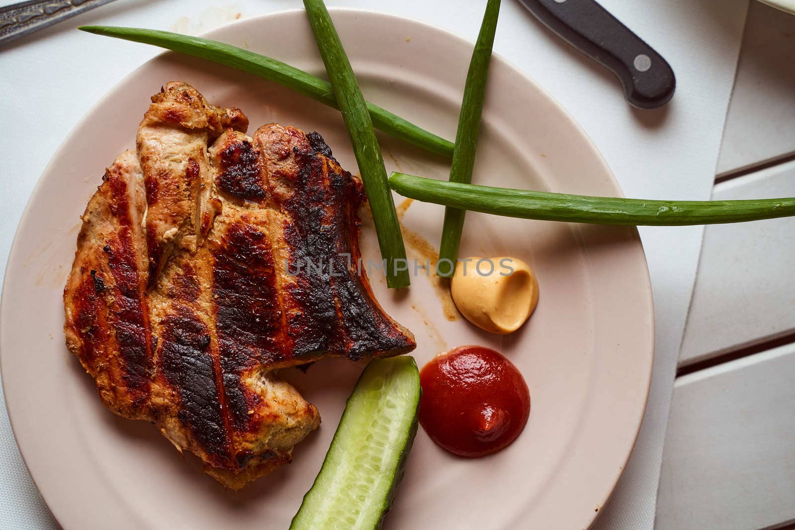 Ready pork steak in a white plate with green onions on a white plate. With copy space. High quality photo