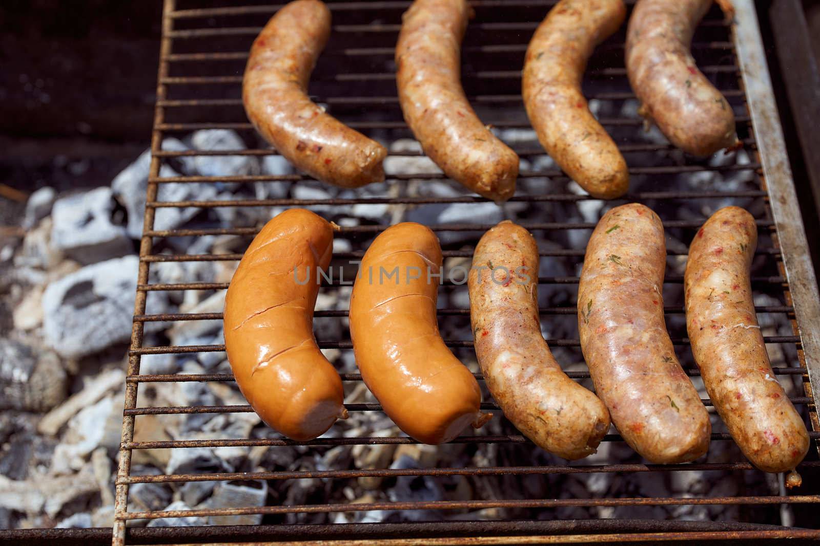 Homemade grilled meat sausages in a white plate on a green background. High quality photo