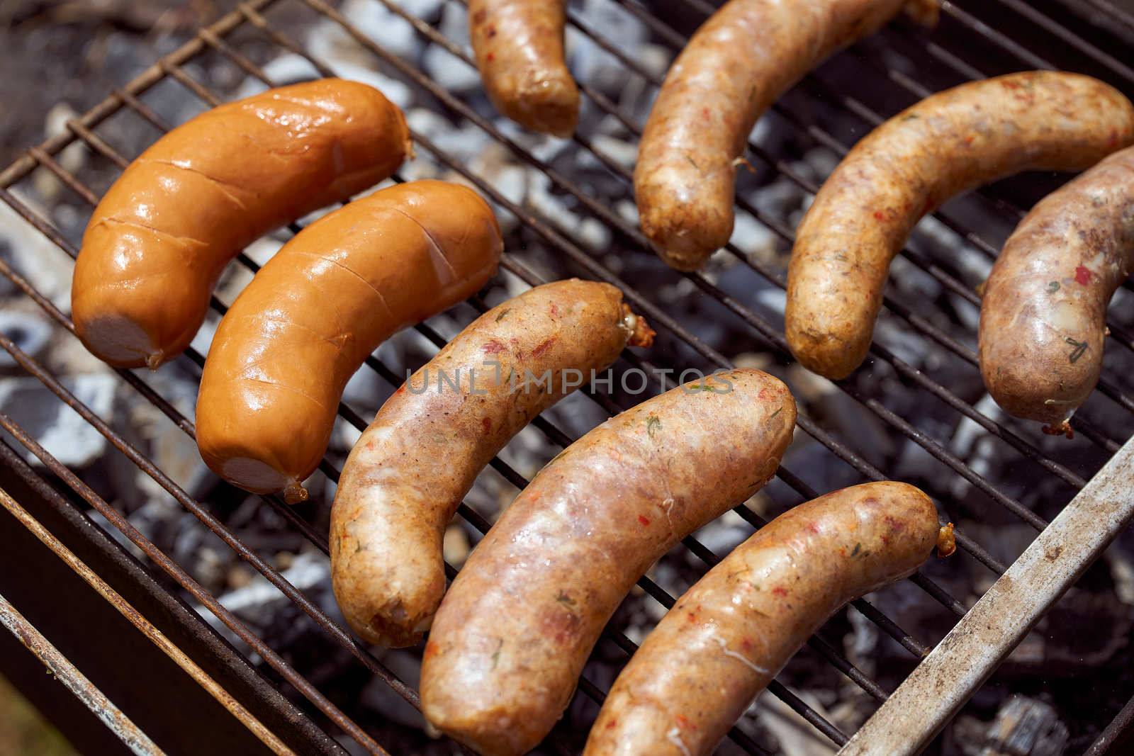 Homemade grilled meat sausages in a white plate on a green background. High quality photo